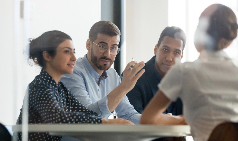 A group of 4 people sit around a table in discussion