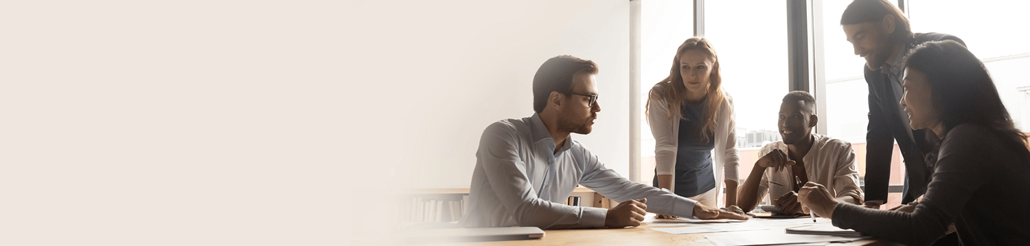 A group of 5 people sit at a table and work together