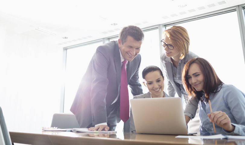 A group of four people work together around a computer