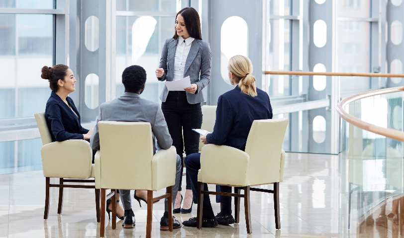 A woman stands in front of three other people and gives a presentation