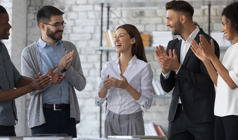 A woman receives recognition from a group of people who clap