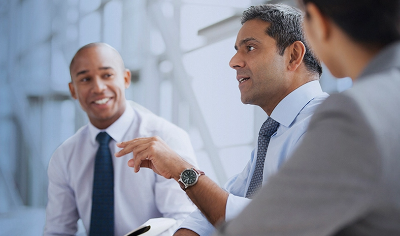 3 men sit together in discussion