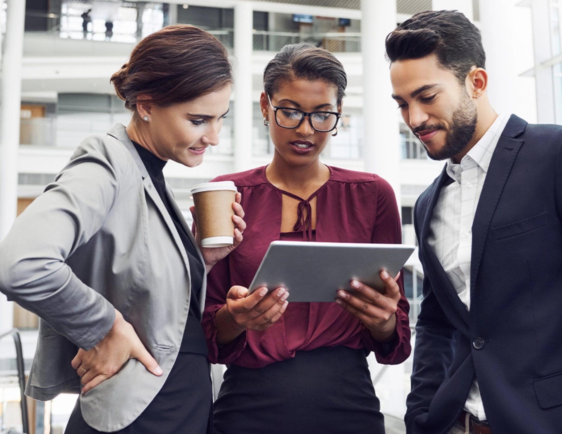 A group of three people look at a tablet together